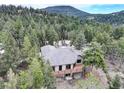The back of the property features a large wooden deck with black metal railings, and a ground-level patio area at 9299 William Cody Dr, Evergreen, CO 80439