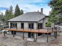 The back of the property features a large wooden deck with black metal railings, and a ground-level patio area at 9299 William Cody Dr, Evergreen, CO 80439