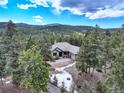 Charming single-story home with a well-maintained lawn, mature trees, and a paved driveway at 9299 William Cody Dr, Evergreen, CO 80439