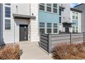 Close up of a modern townhome exterior featuring a gray front door and a gray horizontal fence at 16261 Bolling Dr, Denver, CO 80239