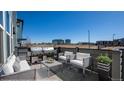 Comfortable outdoor patio featuring a built-in grill, sofa, and matching chairs with views of nearby buildings at 16261 Bolling Dr, Denver, CO 80239