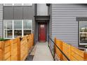 Inviting townhouse entrance with a red door, modern gray siding, and a charming wooden fence at 9445 W 58Th Cir # B, Arvada, CO 80002