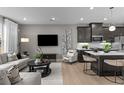 Open-concept living room and kitchen with sleek gray cabinets, stainless steel appliances, and a stylish island at 9445 W 58Th Cir # B, Arvada, CO 80002