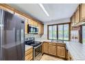 Well-lit kitchen featuring wooden cabinets, modern appliances, and a view of the backyard at 16293 E Brown Pl, Aurora, CO 80013