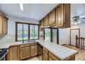 Cozy kitchen featuring wood cabinets, tile countertops, stainless steel dishwasher, and natural light at 16293 E Brown Pl, Aurora, CO 80013