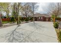 A well-kept lawn surrounded by manicured trees and a concrete driveway in front of a brick house at 3021 Grape St, Denver, CO 80207