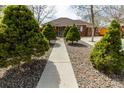 Landscaped front yard with gravel, mature trees, and a concrete path to the home at 3021 Grape St, Denver, CO 80207