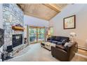 Cozy living room with a stone fireplace, wood ceiling, comfortable seating, and access to the balcony at 180 Broken Lance Dr # 14, Breckenridge, CO 80424