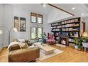 Bright living room featuring high ceilings, many windows, a leather sofa, stylish furnishings, hardwood flooring, and bookshelves at 23646 Genesee Village Rd, Golden, CO 80401