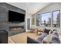 Modern living room with fireplace, large TV, comfortable seating, and picturesque winter views at 578 American Way, Breckenridge, CO 80424