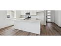 Open-concept kitchen featuring a large center island, modern white cabinets and stainless appliances at 6974 E 126Th Dr, Thornton, CO 80602