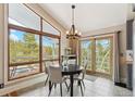 Cozy dining area bathed in natural light, complemented by elegant chandelier and scenic outdoor views at 779 Aspen Way, Evergreen, CO 80439