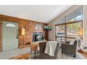 Inviting living room with a wooden accent wall, cozy fireplace, and large windows showcasing beautiful views at 779 Aspen Way, Evergreen, CO 80439