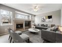 Cozy living room features a fireplace, a large gray sectional sofa, and large windows that provide plenty of light at 6485 Silverleaf Ave, Firestone, CO 80504