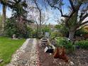 Idyllic backyard featuring a stone pathway, garden beds, and mature trees, creating a tranquil outdoor space at 12622 W Radcliff Ave, Morrison, CO 80465