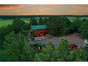 Aerial view of a log cabin home surrounded by lush green trees and open fields at 1353 S Elbert St, Elizabeth, CO 80107