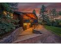 Log cabin home with a covered deck, stone stairs, and landscaped surroundings at 1353 S Elbert St, Elizabeth, CO 80107
