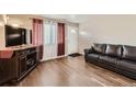 Inviting living room with hardwood floors, a modern TV stand, and a comfortable leather sofa at 465 Miller Ave, Brighton, CO 80601