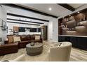 An open living room features exposed beams, a comfortable leather sofa, and a stylish bar area at 16244 Thunder Cat Way, Monument, CO 80132