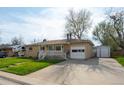 Ranch-style home with a brick facade, covered porch, attached garage, and paved driveway at 6705 Nelson St, Arvada, CO 80004