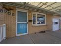 Covered front porch with brick facade and blue door featuring a storm door at 6705 Nelson St, Arvada, CO 80004