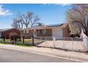 Brick ranch-style home with gated driveway, solar panels, and front yard at 5519 Tucson St, Denver, CO 80239