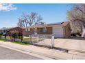 Brick ranch-style home featuring a gated driveway, solar panels, and well-maintained landscaping at 5519 Tucson St, Denver, CO 80239