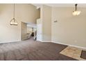 Open living area with high ceilings, neutral carpet, and view into adjacent room at 4713 S Ireland St, Aurora, CO 80015