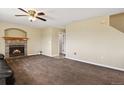 Cozy living room with a brick fireplace, a ceiling fan, and neutral carpet for comfort at 4713 S Ireland St, Aurora, CO 80015