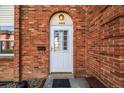 Close up of front door in brick facade with arched entry and white door at 4445 S Lowell Blvd, Denver, CO 80236