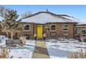 Brick Ranch home with yellow door and snowy front yard at 543 S Bryant St, Denver, CO 80219