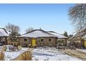 Brick Ranch home with yellow door, snowy yard, and mature trees at 543 S Bryant St, Denver, CO 80219