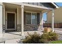Inviting front porch featuring stone accents, providing a charming and welcoming entrance to the home at 47341 Lily Ave, Bennett, CO 80102