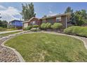 Beautifully landscaped front yard with lush lawn, mature shrubs, and attractive brick facade at 6769 W 70Th Ave, Arvada, CO 80003
