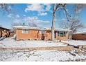 Brick ranch house with a snow-covered front yard and large trees at 3345 W Aqueduct Ave, Littleton, CO 80123