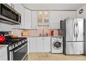 View of kitchen featuring modern white cabinets, stainless steel appliances, granite countertops, and in-unit washer at 800 N Washington St # 710, Denver, CO 80203