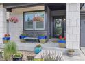 A cozy front porch with hanging flower baskets, potted plants, and bench seating with blue cushions at 16486 W 94Th Dr, Arvada, CO 80007