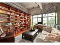 Inviting living room boasts hardwood floors, stylish furniture, and a wall of bookshelves and hanging bicycles at 2000 Little Raven St # 1B, Denver, CO 80202