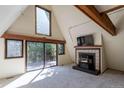 Bright living room with a fireplace and large windows offering views of the deck and lush greenery at 100 Aspen Ln, Evergreen, CO 80439