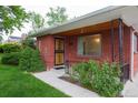 Cozy front porch of a brick home with decorative metal security door and well manicured landscaping at 3222 Fenton St, Wheat Ridge, CO 80212