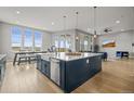 Gourmet kitchen boasts a stainless steel farmhouse sink, expansive island, and seamless transition to the living area at 14341 Beebalm Loop, Parker, CO 80134