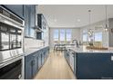 Open kitchen featuring navy blue cabinets, a central island, stainless steel appliances, and hardwood floors at 14341 Beebalm Loop, Parker, CO 80134