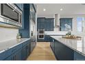 Modern kitchen featuring navy blue cabinets, stainless steel appliances, a subway tile backsplash, and hardwood flooring at 14341 Beebalm Loop, Parker, CO 80134