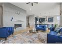 Modern living room with fireplace, bright blue furniture, and an open floor plan leading to the kitchen at 14341 Beebalm Loop, Parker, CO 80134