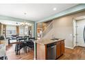 Bright kitchen with an island, stainless steel dishwasher and hardwood floors leading to the living room at 19602 E 63Rd Dr, Aurora, CO 80019