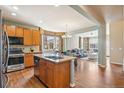 Open kitchen with a large island, granite countertops, stainless steel appliances, and hardwood floors at 19602 E 63Rd Dr, Aurora, CO 80019