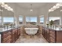 Luxurious bathroom features dual vanities, a soaking tub, and a large window with scenic views at 3535 Medallion Rd, Castle Rock, CO 80104