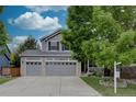 Two-story home features a two-car garage, well-maintained lawn, and mature trees in a tranquil residential setting at 9079 Garnet St, Highlands Ranch, CO 80126
