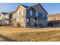 Two-story townhome with stone and siding exterior, landscaped yard, and attached garage at 12713 Leyden St # F, Thornton, CO 80602