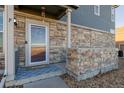 Townhome front entrance with stonework, welcoming mat, and glass door at 12713 Leyden St # F, Thornton, CO 80602